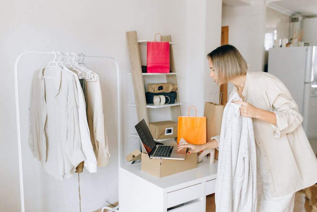 A woman is using a laptop to return a garment.